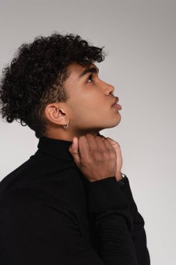 Gri kazak yakasını düzelten Afro-Amerikan adamın yan görüntüsü. 