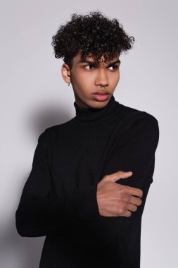 Siyah balıkçı yaka kazak giyen delinmiş Afro-Amerikan adam griye bakıyor.