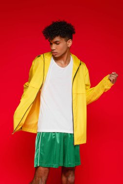 Genç, şık, afro-amerikan adam kırmızı üzerine izole poz veriyor.