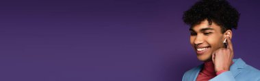 Mor kulaklıklı, kablosuz kulaklıklı mutlu Afro-Amerikan adam.