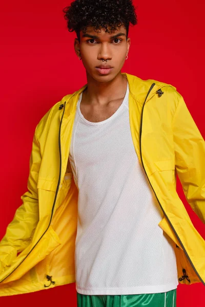 african american man in yellow jacket posing isolated on red