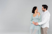 Pregnant woman smiling at husband isolated on grey 