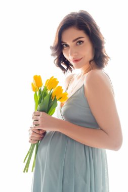 Pregnant woman with yellow tulips looking at camera isolated on white clipart