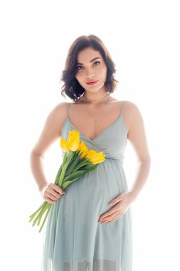 Pregnant woman holding bouquet and looking at camera isolated on white clipart