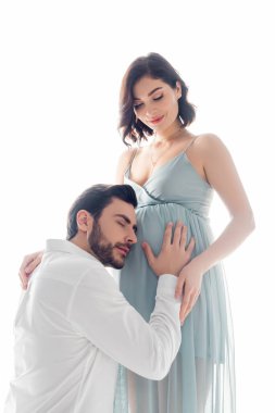 Sakallı adam, hamile bir kadının karnı beyazlar içinde soyutlanmış.