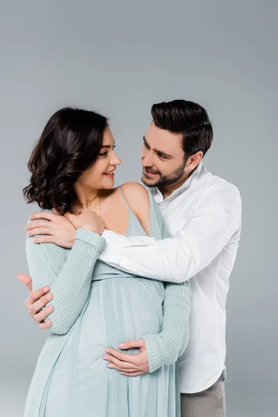 Sorrindo Homem Abraçando Esposa Grávida Vestido Isolado Cinza — Fotografia de Stock