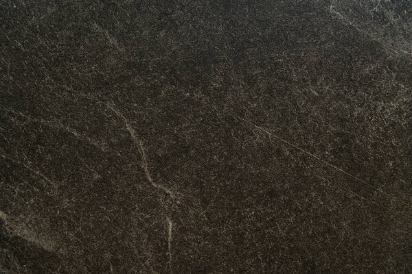 background of black marble surface with streaks, top view