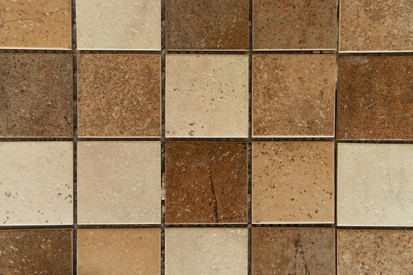 background of square ceramic tiles, with brown and beige stone imitation, top view