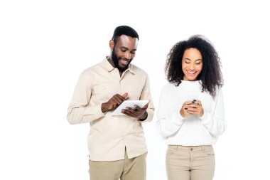 Dijital tabletli gülümseyen Afrikalı Amerikalı adam. Yanında neşeli bir eş. Akıllı telefondan mesaj atıyor.