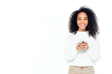 Mutlu Afro-Amerikan kadın cep telefonuyla mesajlaşırken kameraya gülümsüyor.