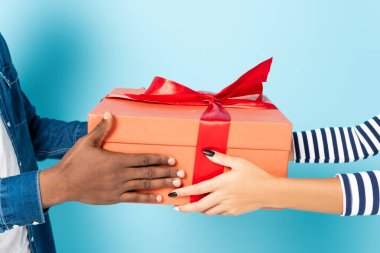 cropped view of african american husband and wife holding gift box on blue clipart