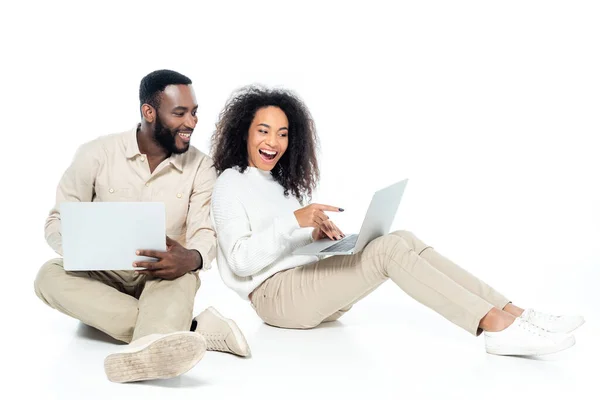 Zdumiona Afroamerykanka Wskazująca Laptopa Pobliżu Uśmiechniętego Męża Białym — Zdjęcie stockowe