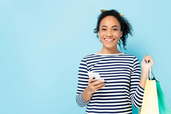 Happy African American Woman Holding Smartphone Shopping Bags Isolated Blue — Stock Photo, Image