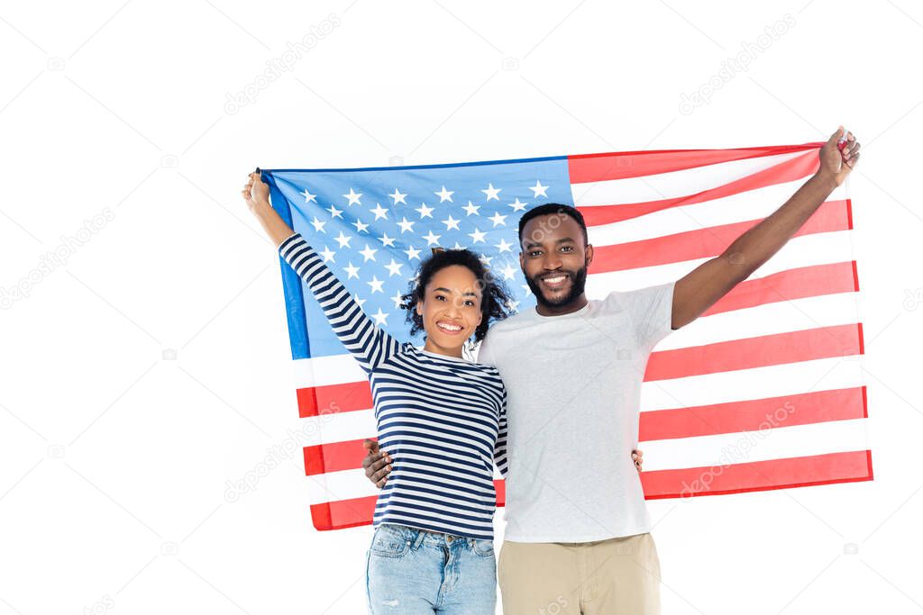 joyful african american couple holding usa flag while looking at camera isolated on white