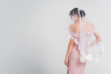 Gri renkte soyutlanmış zarif elbiseli ve peçeli genç bir kadın.