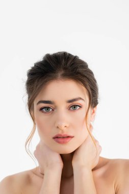 Güzel, doğal makyajlı genç bir kadın beyaz kameraya bakıyor.