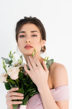 Çekici bir kadın kameraya bakarken elinde beyaz bir buket var.