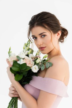 Şehvetli, esmer kadın kameraya bakarken düğün buketini beyaz üzerinde izole halde tutuyor.