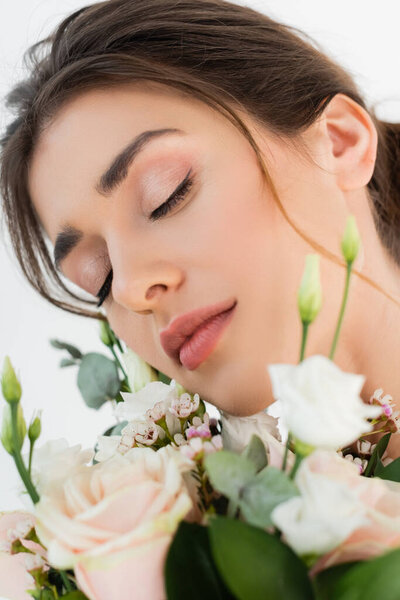 close up view of young woman with natural makeup near wedding bouquet isolated on white