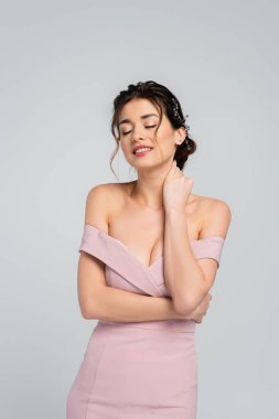 Gülümseyen gelin boynuna dokunurken, gözleri kapalı gri renkte poz veriyor.