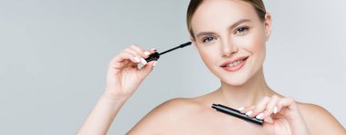 Gri pankartta rimel tutan mutlu genç bir kadın.