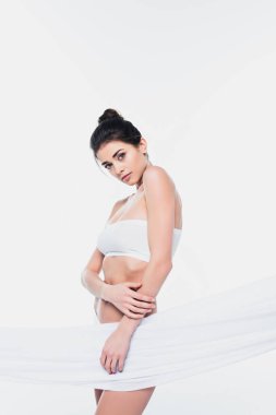 Beyaz tekstil yakınında poz veren sütyenli güzel bir kadın. 