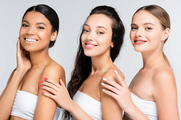 Различные многоэтнические женщины, улыбающиеся изолированно на сером 