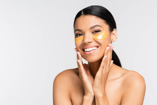 счастливая африканская американка в золотых повязках на глазу улыбается изолированно на белом