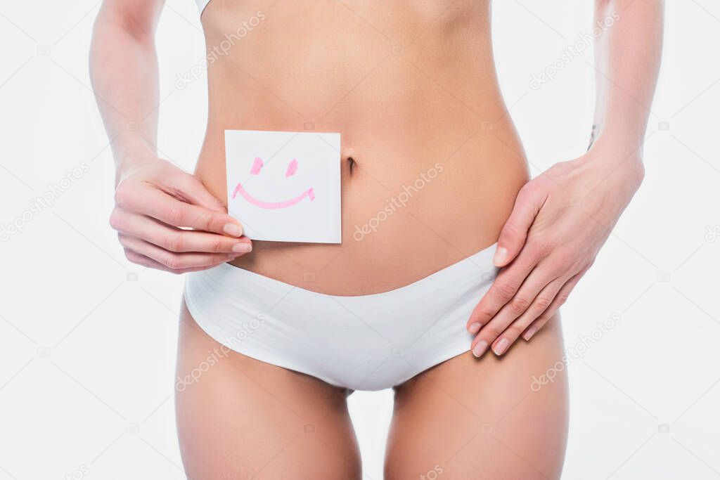 Cropped view of woman in panties holding card with smile sign isolated on white 