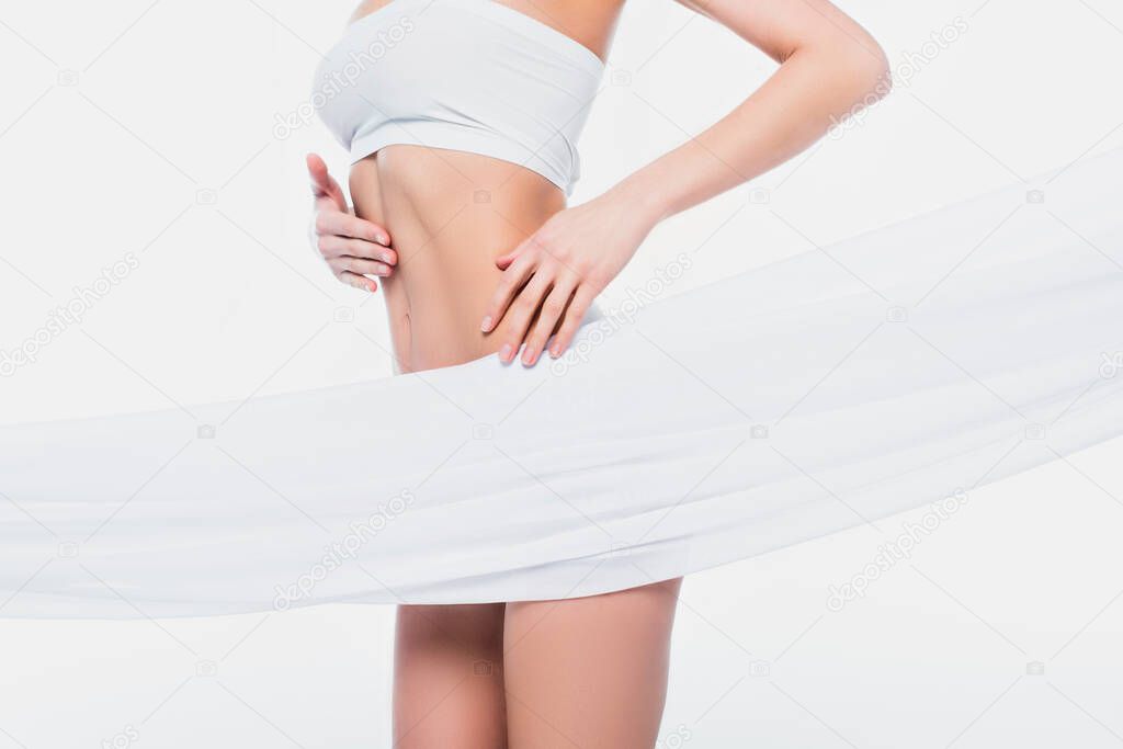 Cropped view of fit woman in bra standing near cloth isolated on white 