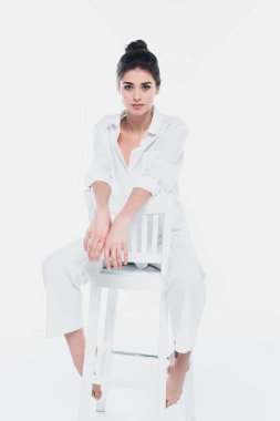 Beyaz elbiseli güzel kadın beyaz sandalyede tek başına oturuyor. 