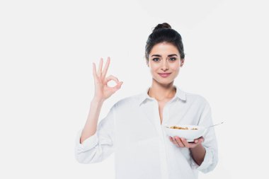 Tahıl gevreğiyle pozitif esmer bir kadın beyaz üzerinde izole edilmiş iyi bir jest gösteriyor. 