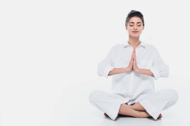 Beyaz elbiseli esmer kadın beyaz arka planda yoga yapıyor. 