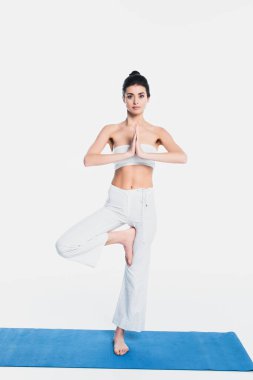 Çıplak ayaklı kadın yoga pozisyonunda, spor minderinin üstünde, beyaz tenli. 