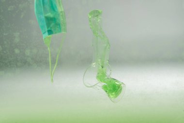 Tıbbi maske, plastik torba ve bardak suyun altında, ekoloji konsepti