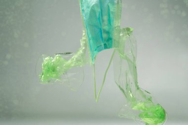 Tıbbi maske altında plastik poşetler ve fincanlar, ekoloji konsepti