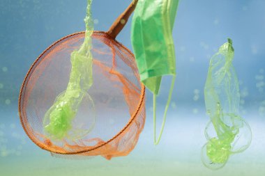 Tıbbi maskeye yakın kepçe ve suda plastik torbalar, ekoloji konsepti