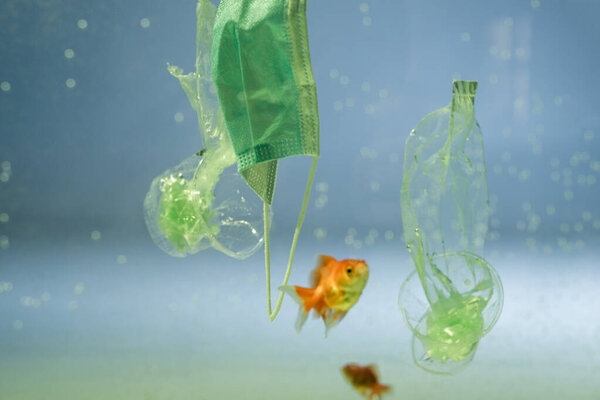 fish near medical mask, plastic bags and cups in water, ecology concept