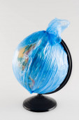 Globus verpackt in Plastiktüte isoliert auf grau, ökologisches Konzept