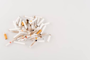 plenty of cigarette ends on white surface, ecology concept, top view clipart