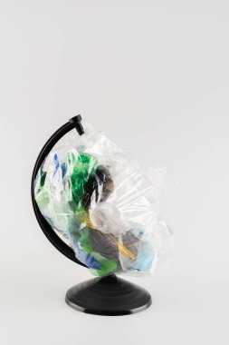 Dünya üzerinde plastik çöplerle dolu selofan paketi gri ekoloji kavramına izole edilmiş.