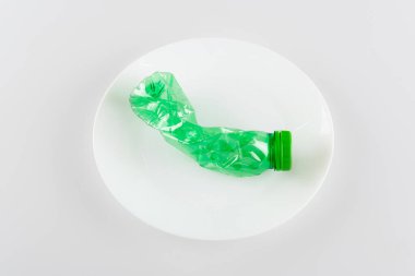 top view of plate with used plastic bottle on white, ecology concept clipart