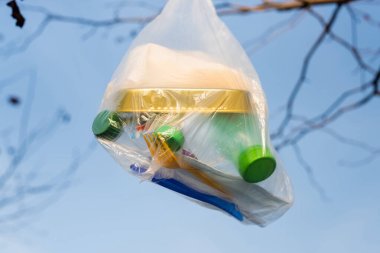 Kutu ve plastik şişelerle dolu polietilen çanta mavi gökyüzüne karşı, ekoloji kavramı