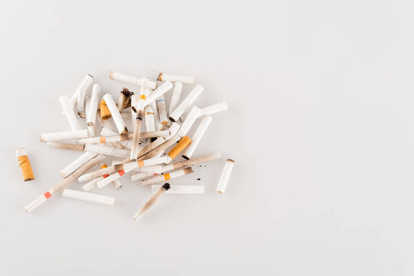 plenty of cigarette ends on white surface, ecology concept, top view