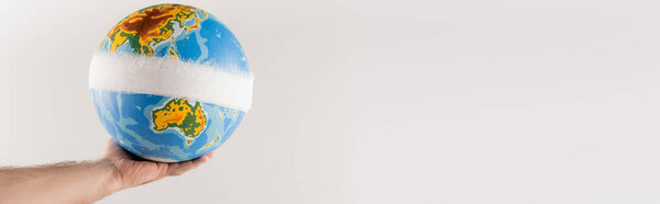 частичный вид мужской руки с перевязанным глобусом, изолированный на сером, экологическая концепция, баннер