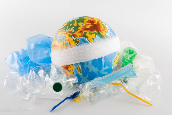 перевязанный глобус возле пластикового мусора на сером, экологическая концепция