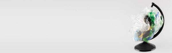 целлофановый пакет с пластиковым мусором на земном шаре стенд изолирован на сером, экологическая концепция, баннер