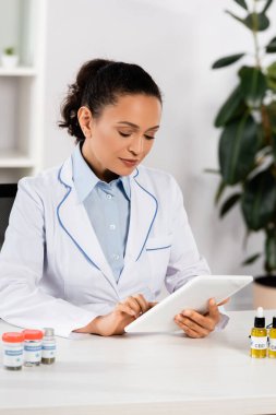 Beyaz önlüklü Afrikalı Amerikalı doktor klinikte dijital tablet kullanıyor.