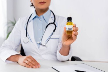 cropped view of african american doctor holding bottle with cbd lettering  clipart