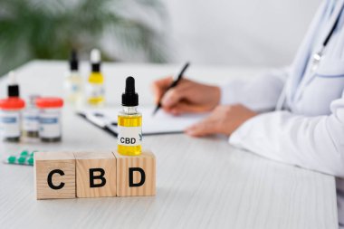 Cbd küplerinin yanında reçete yazan doktor manzarası ve masadaki ilaçlar.